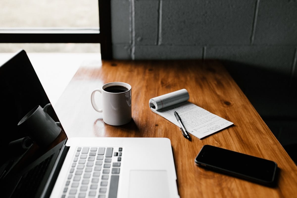 A laptop and a cup of coffee on a warm wooden table